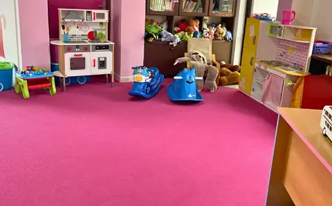 Kuchyňka na hraní a odrážedla na růžovém koberci