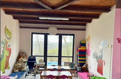 Herna pod tmavými trámy, na stěnách malovaný drak a princezna, stolečky u velkých oken